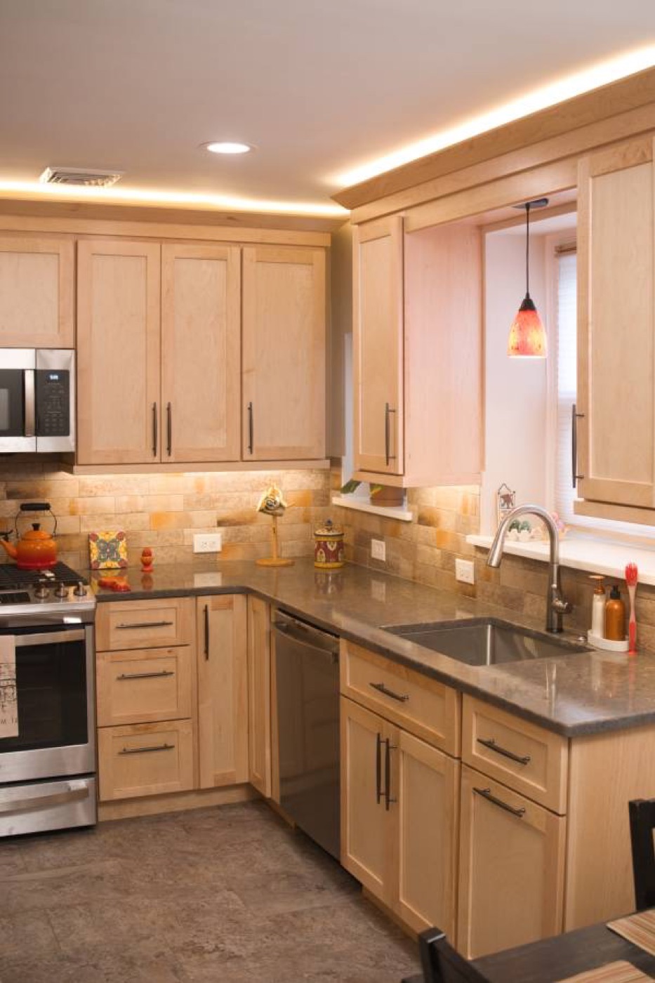 Remodeled kitchen with maple shaker cabinets, stone tile backsplash, and stainless steel appliances